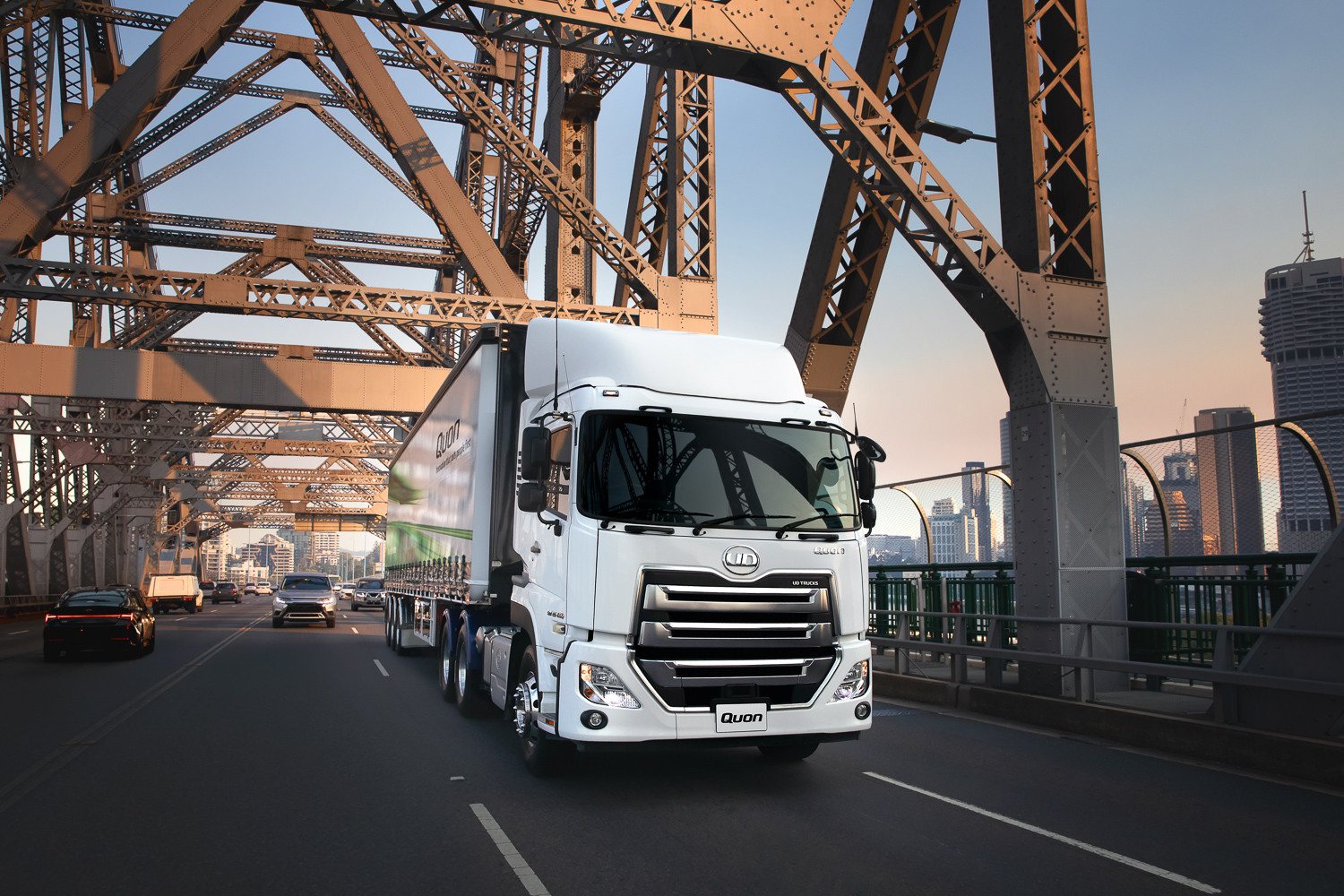 White semi-truck crossing a city bridge at sunset