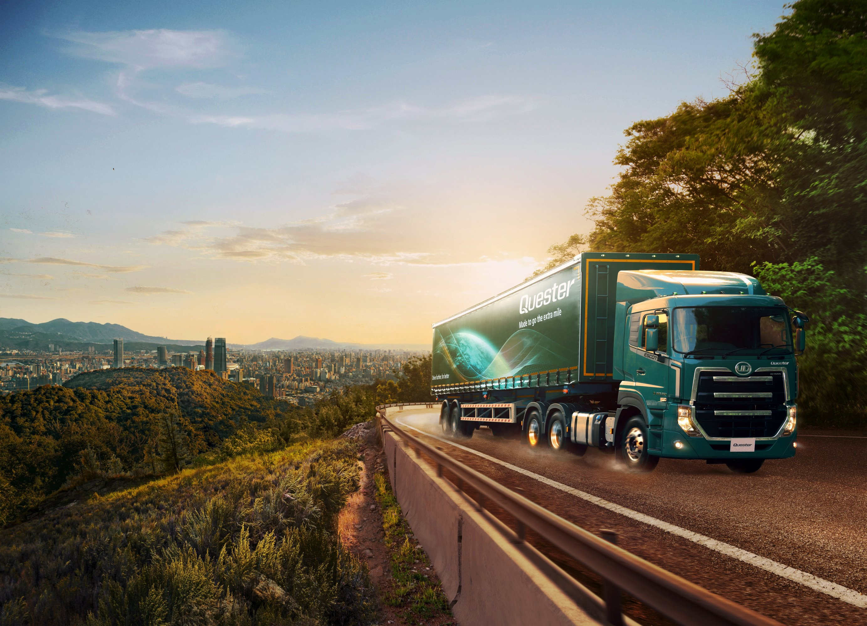 Lori kubwa kijani kwenye barabara, jua linachomoza, mji uko mbali.