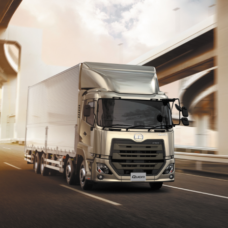 高速道路を走る大型トラック。背景に高架橋と夕焼け空。