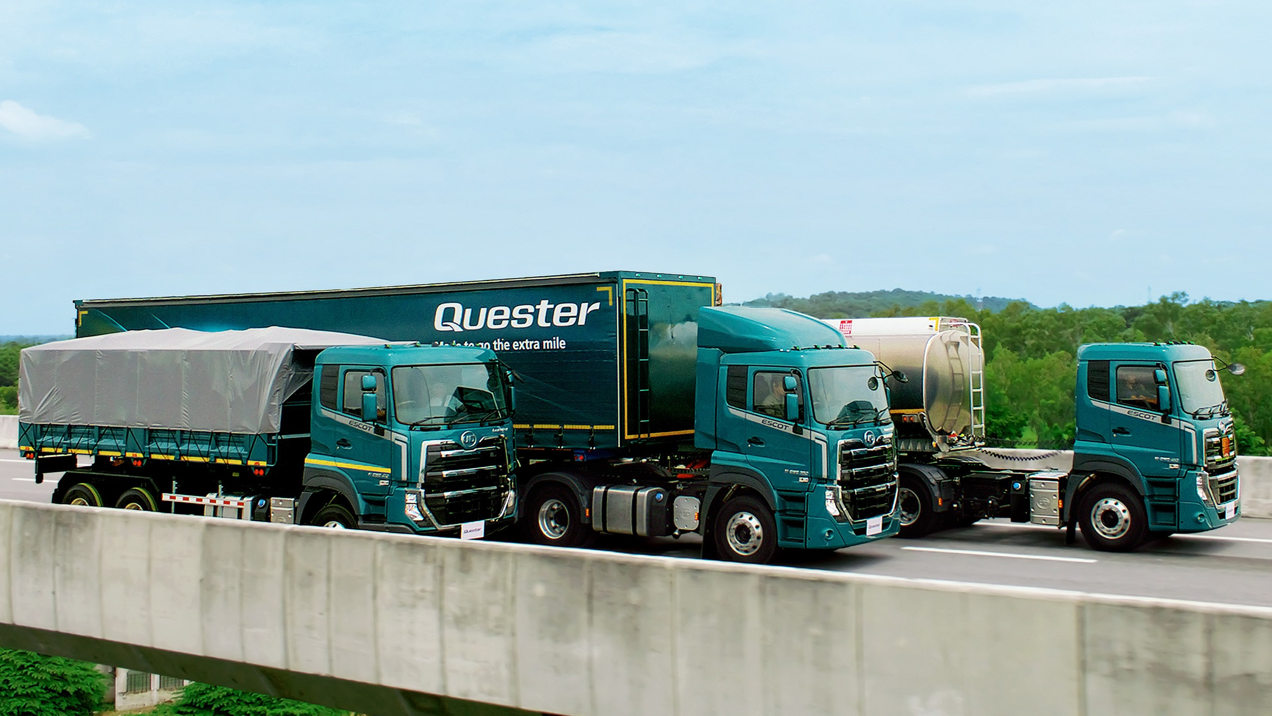 Malori matatu ya kijani yamesimama juu ya daraja chini ya anga ya buluu.