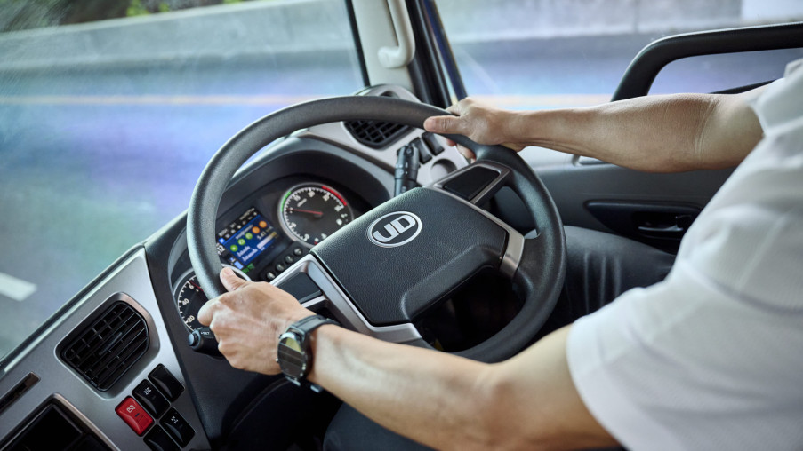 運転手が両手でトラックのハンドルを握って運転している様子