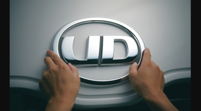 両手で触れられているUDロゴの車のエンブレム