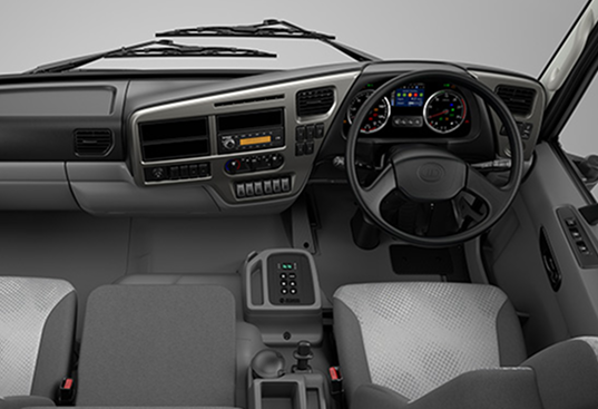 Kabin trak dengan papan pemuka moden, stereng, dan kerusi kelabu.